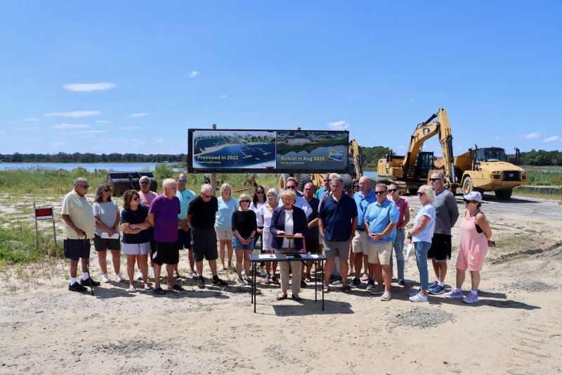Jane Brady announces a lawsuit filed by some residents of Osprey Point against NVR, the parent company of NV Homes. She is joined by Osprey Point residents in the area where promised water access amenities were to be built. The images show NV Homes marketing that depicts the amenities planned and a recent photo of the site. The promised amenities include a beach, boat slips and a kayak launch into Arnell Creek. BILL SHULL PHOTOS